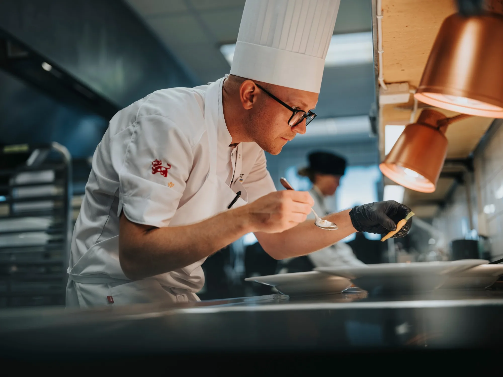 A chef finishing a plate with sauce